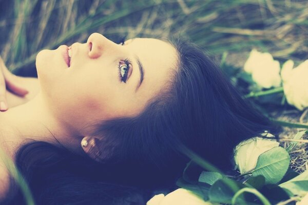 A girl with blue eyes is lying on the grass