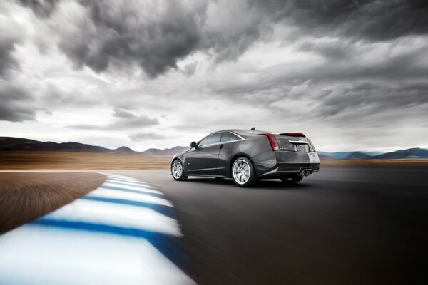 Cadillac on a high-speed highway under a gray overcast sky