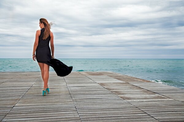 Mädchen im schwarzen Kleid am Meer