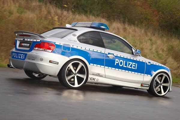 Auto della polizia bianca e blu sulla strada bagnata