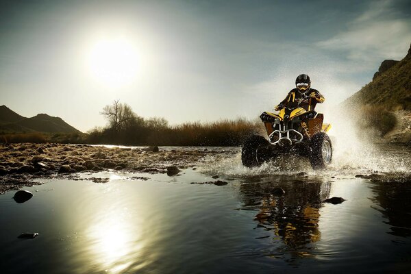 Quad-Bike fährt mit Spritzwasser über eine Pfütze