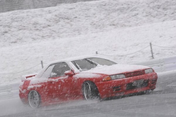 Deriva en la nieve del coche rojo durante la mañana de invierno