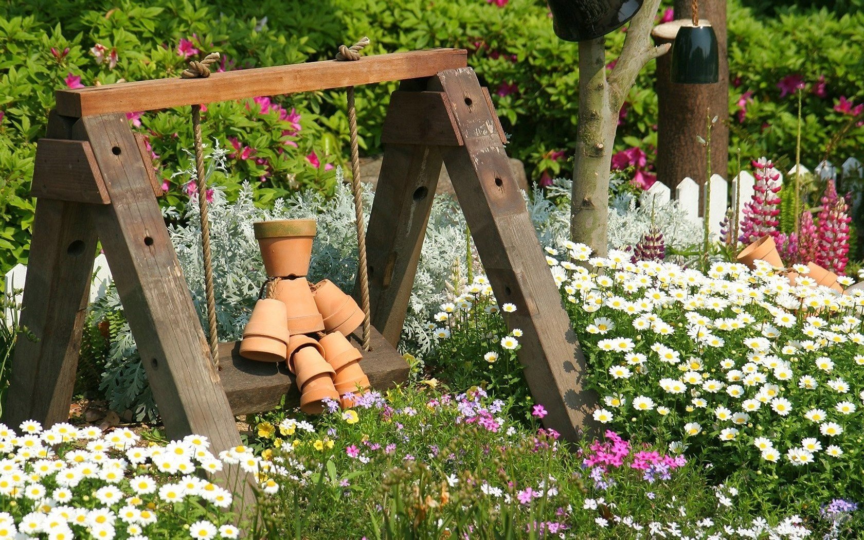 holzschaukel blumen zaun töpfe kamillenfeld töpfe feld sommer holz gänseblümchen gras büsche