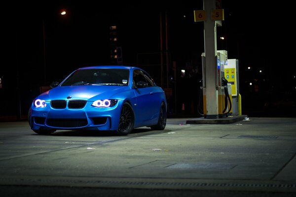 Blaues Auto nachts an der Tankstelle