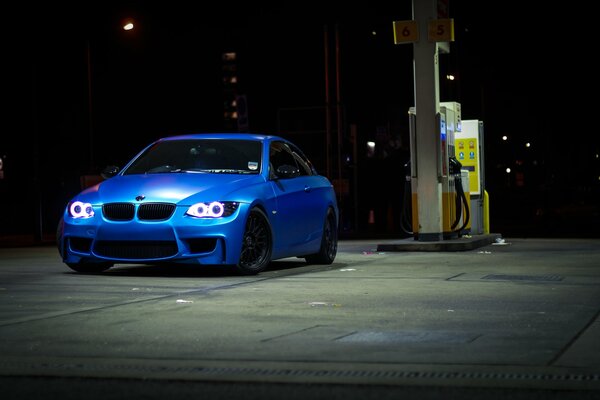 Voiture bleue dans la nuit à la station-service