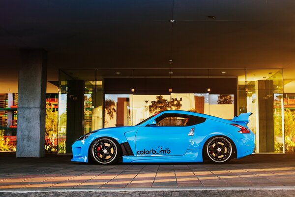 Das getunte Auto nissan 370z in leuchtend blauer Farbe vor dem Hintergrund der modernen Architektur