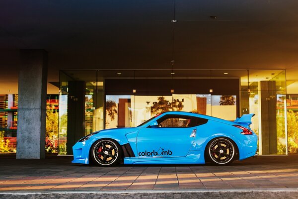 Tuned nissan 370z car in bright blue color against the background of modern architecture