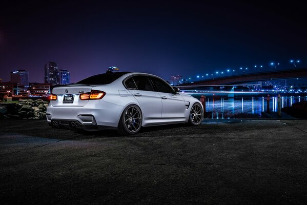 Weißer bmw m3 f80 auf dem Hintergrund der Brücke und des Flusses