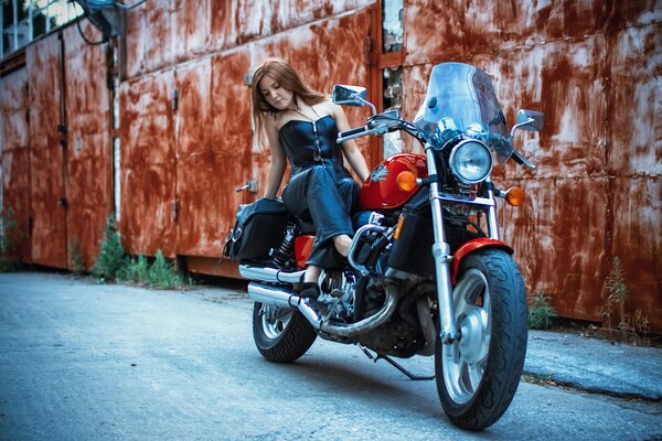 Ragazza seduta su una moto sullo sfondo della parete