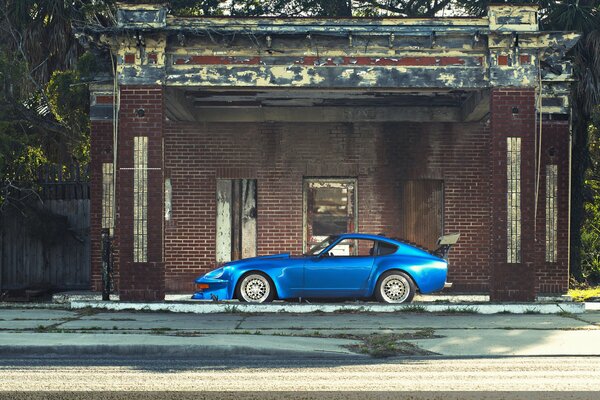 Schickes blaues Datsun 240z vor dem Hintergrund eines verlassenen Hauses