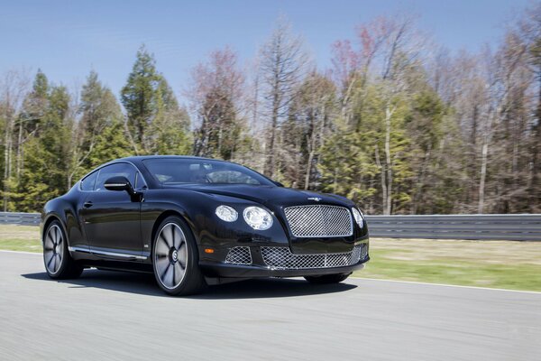 A black Bentley in motion on a country road
