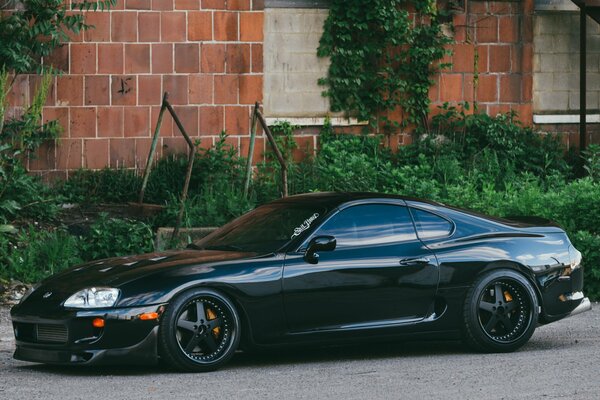 A black sports Toyota is parked against the background of a brick house