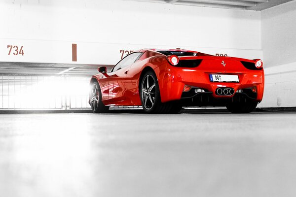 A red Ferrari 458 italia stands in a white room