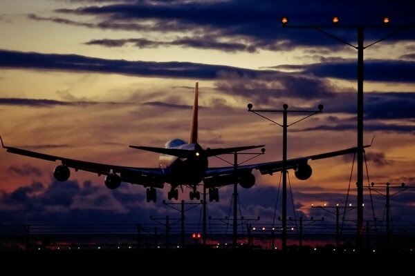 Un aereo si imbarca su una striscia sullo sfondo di un bellissimo tramonto