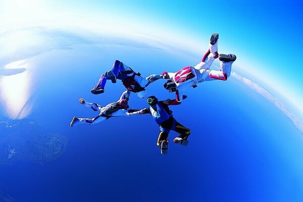 The flight of four parachutists in the blue sky