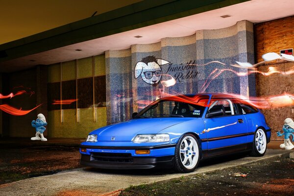 A blue honda is parked in the evening near the villa