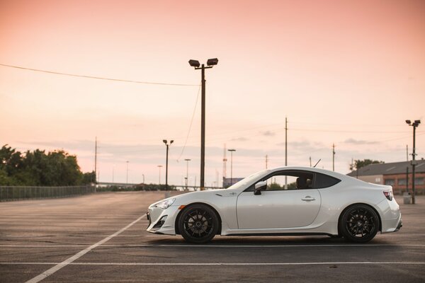 White Subaru coupe in the parking lot