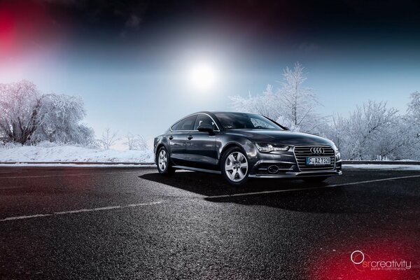 Автомобиль audi a7 на фоне снежных деревьев