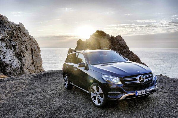 Mercedes auf dem Hintergrund des Meeres. Felsen und Sonnenuntergang