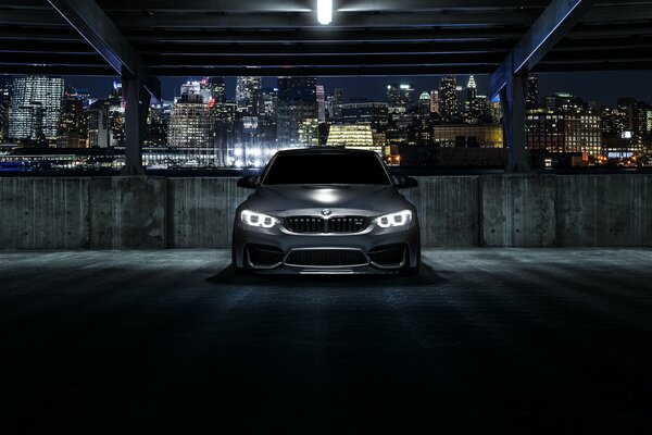 Bmv m3 with headlights on on the background of the night city