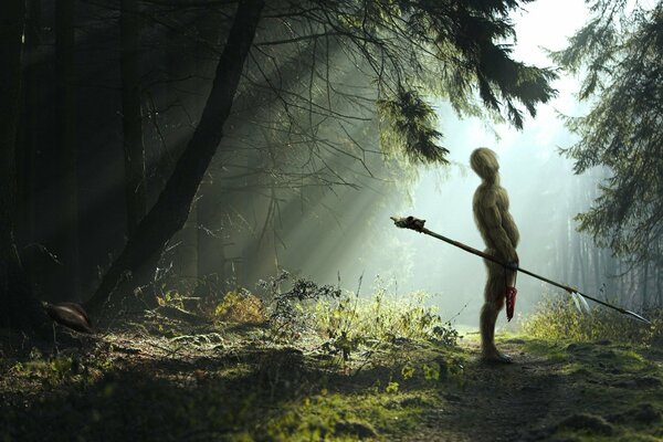 Un hombre con una lanza en el fondo de un bosque denso