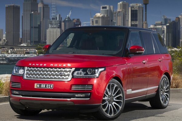 Der rote Range Rover steht seitlich und die Stadt dahinter