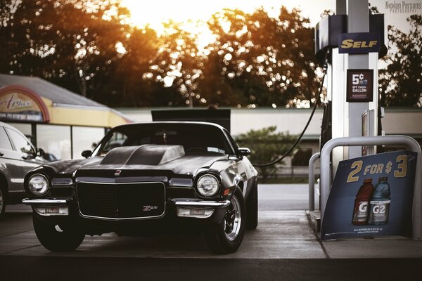 The black car is at the gas station