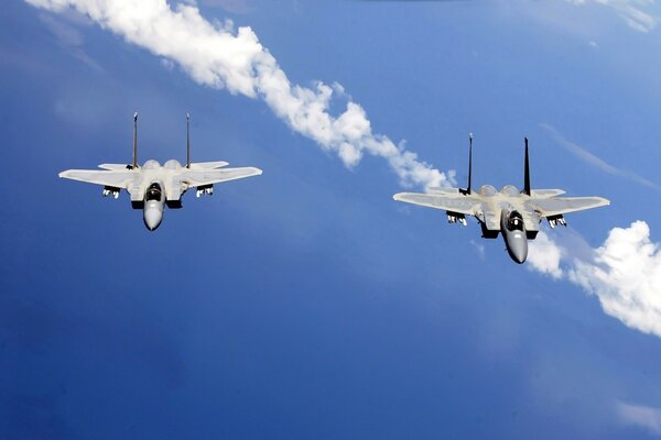 Two fighter jets are flying in the blue sky