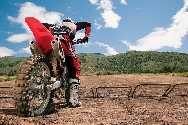 An athlete at the start of a motorcycle trial against the background of hills