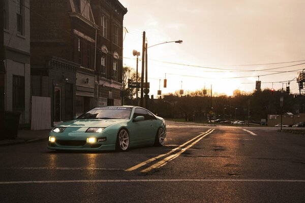 A mint-colored Nissan on the road in the city