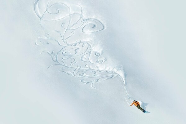 A man on a snowboard creates patterns in the snow