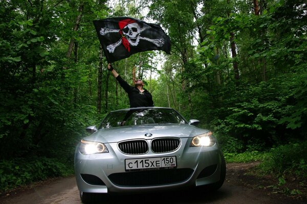 Mann mit Piratenfahne auf grauem BMW in der Waldstraße