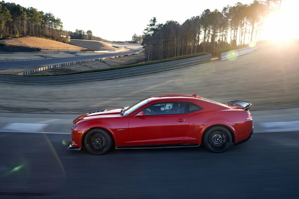 Vue latérale d une belle Chevrolet rouge en mouvement dans les rayons du soleil levant