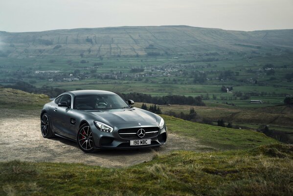 Черный автомобиль mercedes amg посреди горных склонов