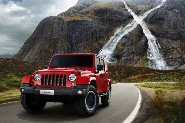 Auto Wrangler X sulla strada di montagna sullo sfondo di una cascata