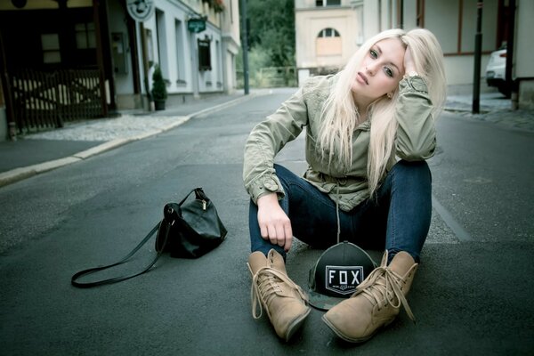 Una ragazza in jeans sull asfalto sta aspettando la felicità