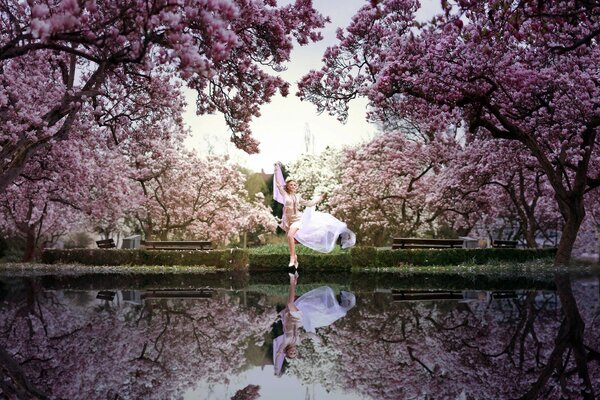 A girl in a park by a lake among flowering trees