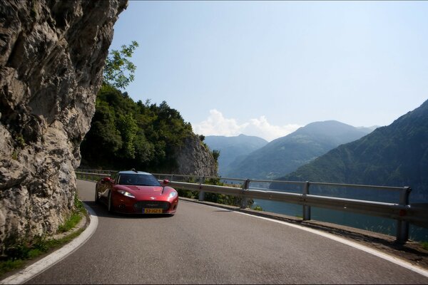 Auto sportiva rossa tra le montagne e la serpentina