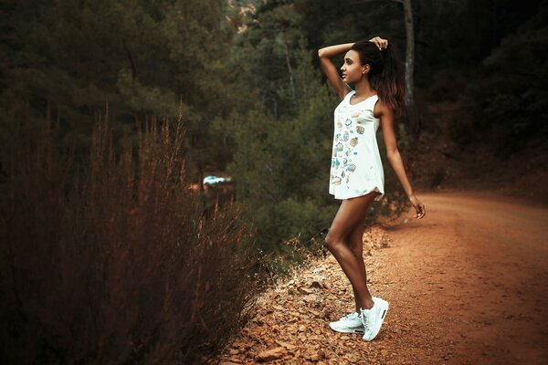 A brunette girl is standing by the side of the road