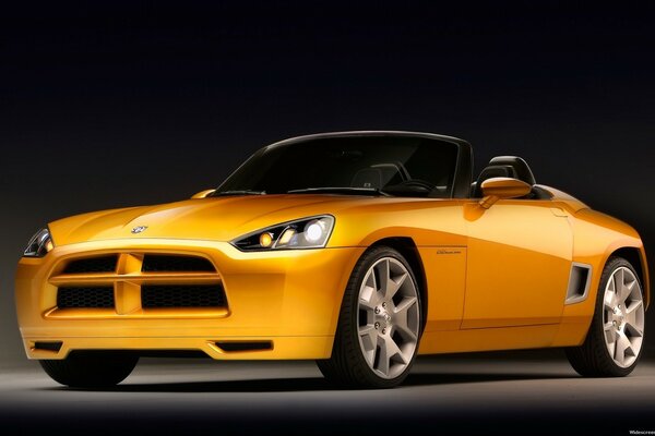 Orange Dodge roadster with an open top on a black background