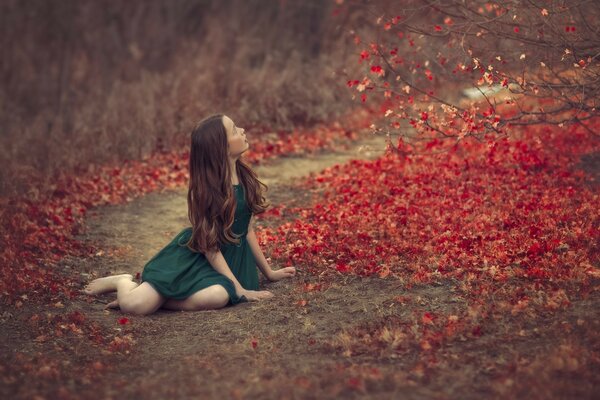 A girl in a green dress is sitting in the foliage