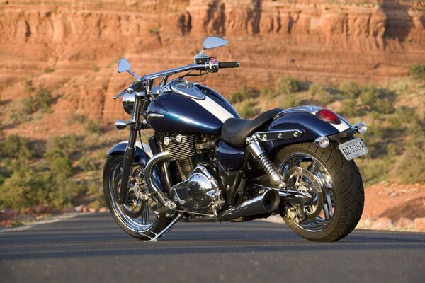 A motorcycle standing on the road near the mountains