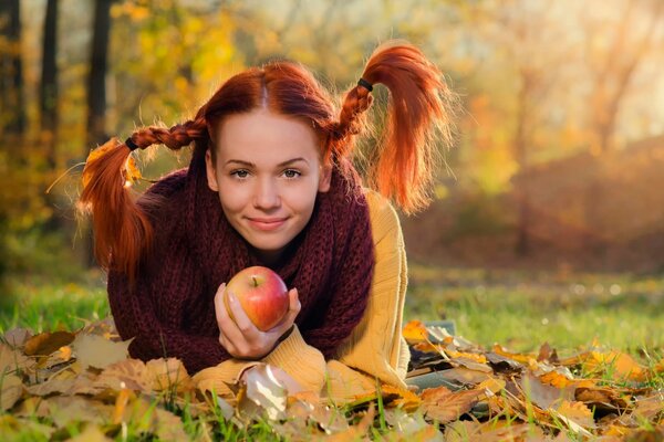 Ruda dziewczyna z jabłkiem w jesiennym oesie