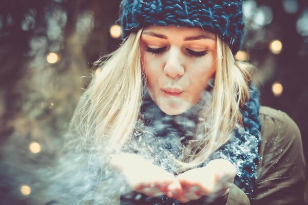 Blonde blows snow from her palms