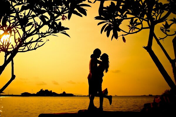 Ein Mann und ein Mädchen umarmen sich vor dem Hintergrund des Sonnenuntergangs