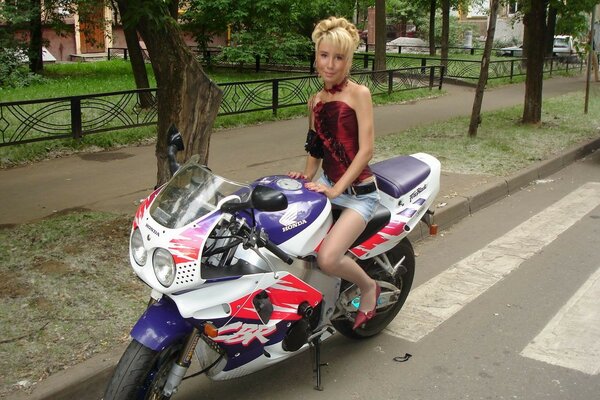 A woman in a miniskirt on a motorcycle on the road