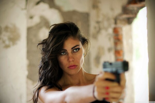 Brunette with a gun aiming at the victim