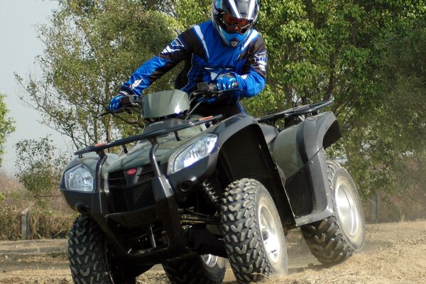 The Kymco ATV leaves a light cloud of dust behind it while driving