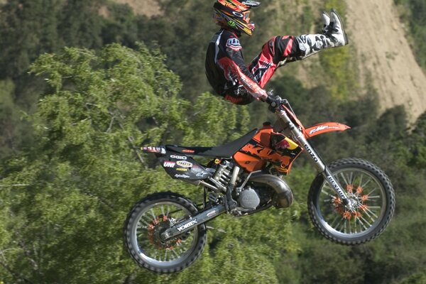 Un motocycliste fait une cascade sur un fond de falaise