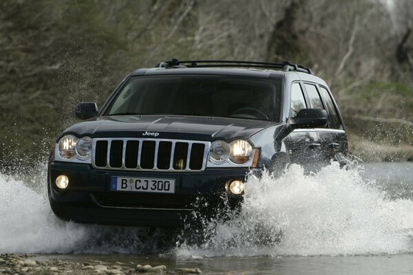 Jeep conduce con confianza en el río en las montañas 